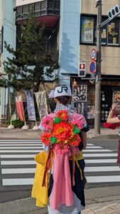 Jeune femme de dos portant un habit traditionnel d'Aomori et un chapeau marqué du logo JR