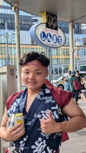 Portrait d'un Japonais de la région Tohoku souriant avec un pouce en l'air et une canette de boisson dans la main