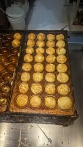 Image de boules de takoyaki dorées et croustillantes, servies avec une garniture de sauce, de mayonnaise et de flocons de bonite, typiques de la cuisine de rue d'Osaka