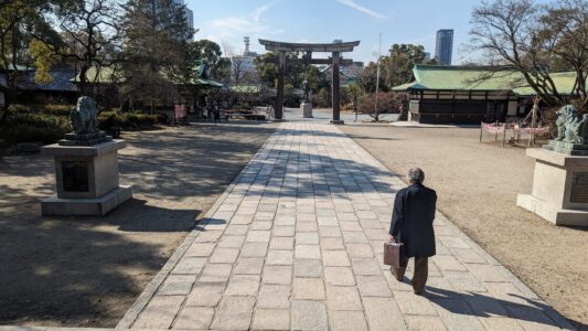 Un homme avec une valise devant un temple à Osaka