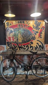 Vélo à l'arrêt devant un restaurant à Dotonbori, Osaka, entouré de néons