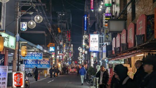 Rue animée de Dotonbori à Osaka la nuit, remplie de passants et d'enseignes lumineuses