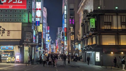 Rue animée de Dotonbori à Osaka avec des passants et des enseignes lumineuses