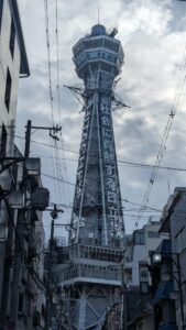 La Tour Tsutenkaku à Osaka se profile sous un ciel nuageux gris, mettant en valeur son architecture emblématique
