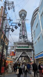 La Tour Tsutenkaku à Osaka se dresse au bout d'une rue animée, entourée de boutiques et de restaurants