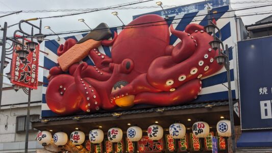 Façade colorée à Shinsekai à Osaka, mettant en avant une représentation de poulpe en rouge, symbole de la cuisine locale