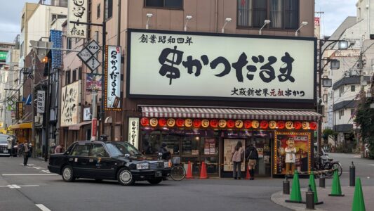 Façade d'un taxi à Shinsekai, Osaka, arborant des couleurs vives et des décorations typiques japonaises