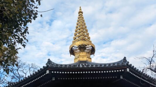 Pointe dorée d'un temple à Osaka, reflétant la lumière du soleil et symbolisant la spiritualité zen japonaise