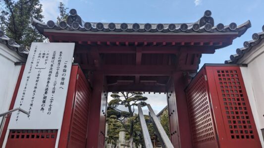 Entrée d'un temple rouge à Osaka, ornée de lanternes et de motifs traditionnels, symbole de spiritualité japonaise