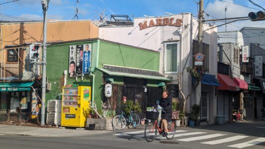 Dans les rues d'Osaka dans le quartier Little Korea Femme à vélo dans une rue de Little Korea à Osaka, Japon, avec une architecture colorée en arrière-plan