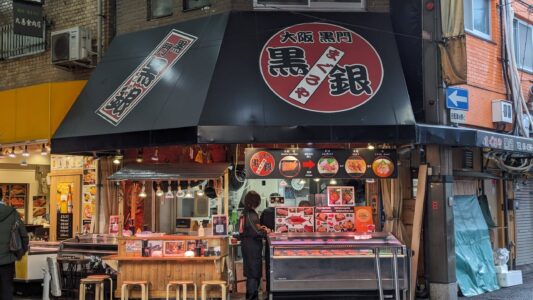 Vitrine de restaurant aux couleurs rouge et noir lors d'un Foodie Tour à Osaka, avec un signe en japonais