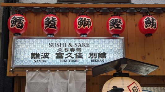 Sushi & Sake Façade d'un magasin à Osaka, décorée de lanternes colorées et d'enseignes lumineuses