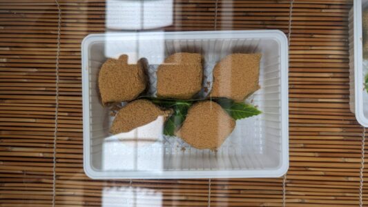 Assortiment de mochis beiges recouverts d'une feuille verte, mettant en valeur une présentation traditionnelle