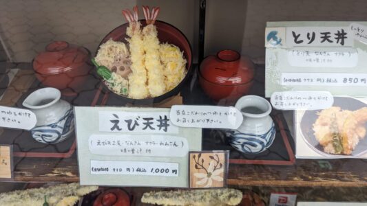 Vitrine d'un restaurant montrant un plat de tempura appétissant avec sauce, mettant en valeur la gastronomie d'Osaka