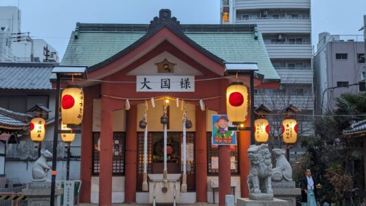 Lanternes traditionnelles illuminées à l'entrée d'un temple zen à Osaka, créant une ambiance spirituelle et apaisante