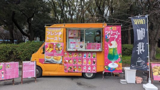 Food truck coloré orange et rose à Osaka, proposant une variété de plats japonais