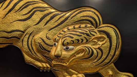 Musée d'art à l'intérieur du château Sculpture dorée en forme de tigre ornant le château d’Osaka, brillamment détaillée et symbolisant la puissance et la protection. La sculpture se détache avec éclat sur la structure historique du château