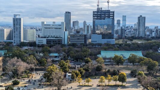 Vue du château d'Osaka avec un parc verdoyant au premier plan et la ville en arrière-plan