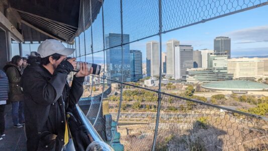 Vue panoramique du château d'Osaka avec un ami mexicain en premier plan, prenant une photographie