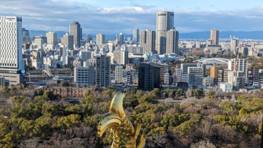 Vue panoramique du château d'Osaka avec une statuette dorée en forme de queue de poisson au premier plan