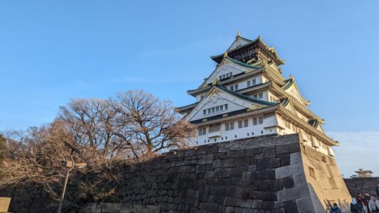 Image du château d'Osaka sous un ciel bleu éclatant, mettant en valeur son architecture majestueuse