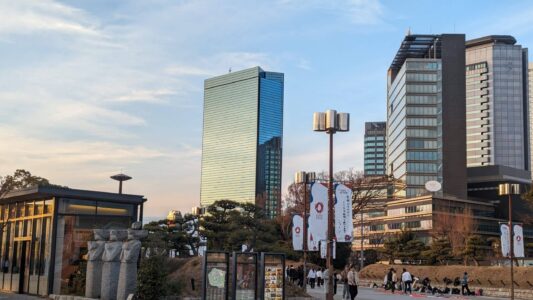 Image du château d'Osaka au cœur de la ville, entouré de gratte-ciel et de nature, symbolisant le contraste entre histoire et modernité