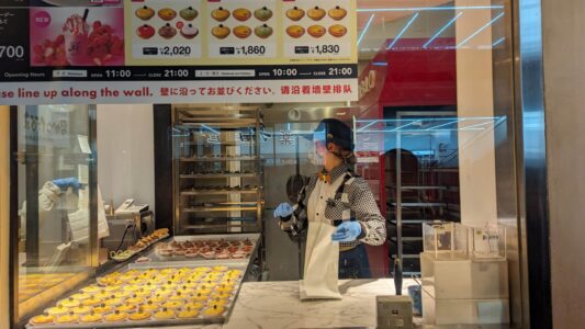 Image de plusieurs mini cheesecakes dorés de Pablo, alignés dans leur boutique à Osaka, avec un intérieur lumineux et accueillant