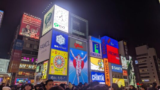 Glico, l'enseigne la plus connue à Osaka Image des enseignes lumineuses de Glico à Dotonbori, Osaka, illuminées pendant la nuit, créant une ambiance animée et festive