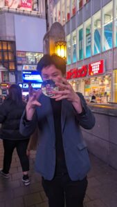 Magicien de rue dans le quartier de Dotonbori Image d'un magicien de rue captivant un public dans le quartier animé de Dotonbori à Osaka, avec des lumières vives et une ambiance festive