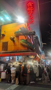 Osaka style Image d'une enseigne lumineuse représentant un dragon dans le quartier animé de Dotonbori à Osaka, entourée d'autres panneaux colorés et de l'animation de la rue