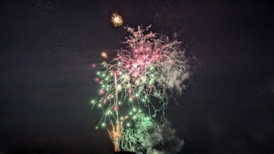 Photographie pendant 2 jours de festival : Scènes locales, chars, défilés & Feux d'Artifice "Défilé nocturne des chars Nebuta illuminés avec des feux d’artifice violets et verts éclatant en arrière-plan lors du festival Nebuta d’Aomori