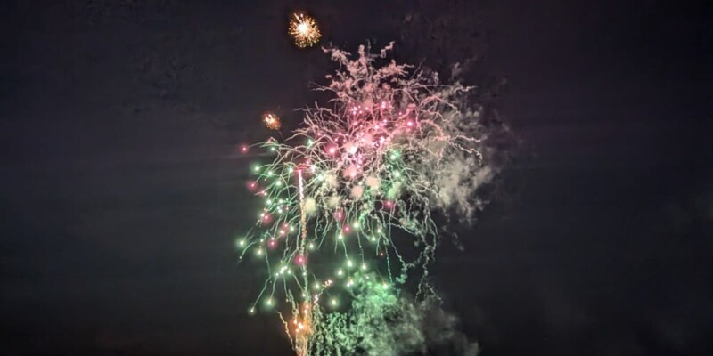Photographie pendant 2 jours de festival : Scènes locales, chars, défilés & Feux d'Artifice "Défilé nocturne des chars Nebuta illuminés avec des feux d’artifice violets et verts éclatant en arrière-plan lors du festival Nebuta d’Aomori