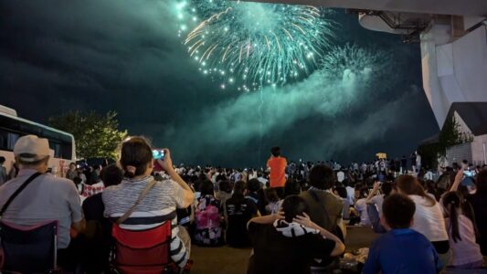 "Photographies du festival Nebuta d'Aomori avec une foule de spectateurs, des chars illuminés entourés de danseurs traditionnels haneto et des feux d’artifice violets et verts éclairant le ciel nocturne