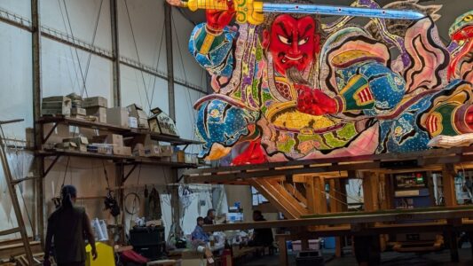 Photographie pendant 2 jours "Photographie de chars Nebuta à l'arrêt pendant le festival, ornés de décorations colorées et illuminés, avec des participants en costumes traditionnels autour