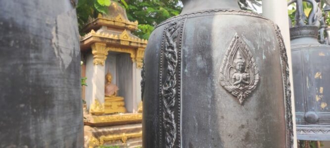 Vue d'un temple à Bangkok avec une cloche ornée et une statue de Bouddha, montrant à la fois l'intérieur décoré et l'extérieur architectural impressionnant
