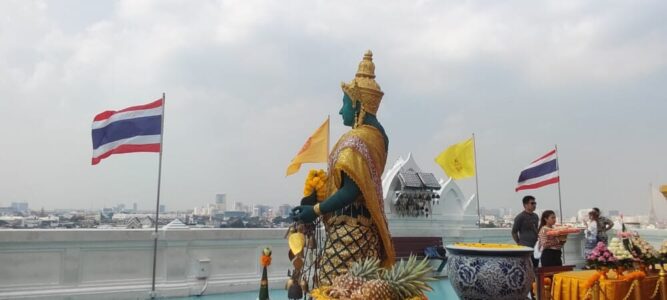 Drapeaux thaïlandais à côté d'une statue près du Chao Phraya