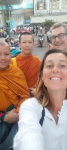 Selfie d'Inès en chemise blanche avec son père et de jeunes moines en robes orange à Bangkok