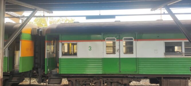 Un train vert vibrant en provenance de Bangkok, filant à travers la campagne thaïlandaise en direction d'Ayutthaya, entouré de paysages luxuriants et de rizières dorées