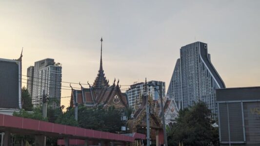 Vue d'un temple traditionnel à côté d'un bâtiment moderne, juste avant le coucher de soleil à Bangkok