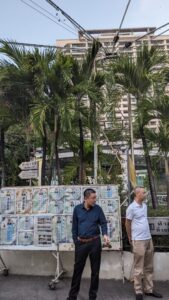 Deux personnes thaïlandaises devant un temple, entourées d'affiches et de monuments
