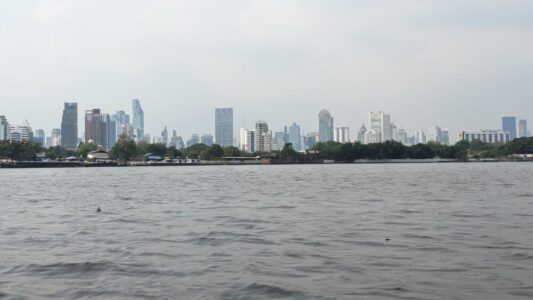 Vue des gratte-ciel de Bangkok depuis le fleuve Chao Phraya, avec le parc Bangkachao en arrière-plan