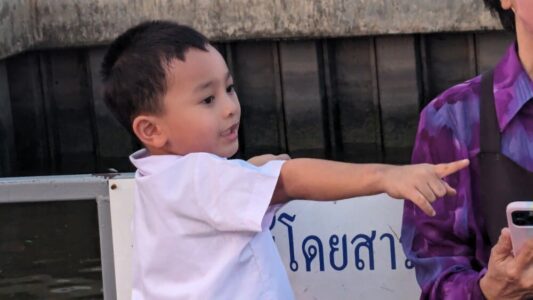 Petit garçon thaïlandais habillé en blanc, pointant du doigt à Bangkok