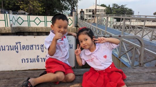 Portrait d'enfants locaux souriant et faisant des grimaces, un garçon et une fille assis sur un banc à Bangkok