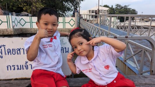 Portrait d'enfants locaux souriant et faisant des grimaces, un garçon et une fille assis sur un banc à Bangkok