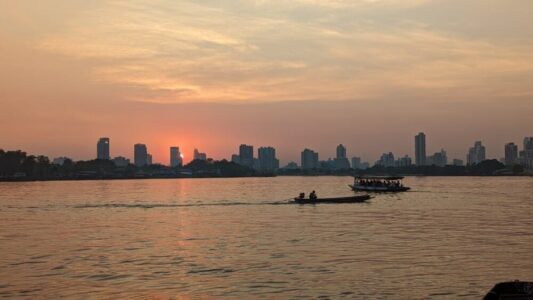Petit bateau de touriste et bateau de pêcheur sur le fleuve au coucher du soleil à Bangkok