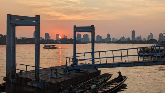 Vue depuis le port d'un petit bateau de touriste et d'un bateau de pêcheur au coucher du soleil à Bangkok
