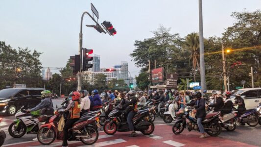 Plusieurs scooters arrêtés à un feu rouge dans les rues animées de Bangkok