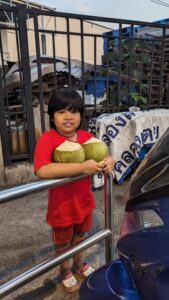 Portrait d'un enfant local souriant, tenant deux noix de coco dans les mains à Bangkok