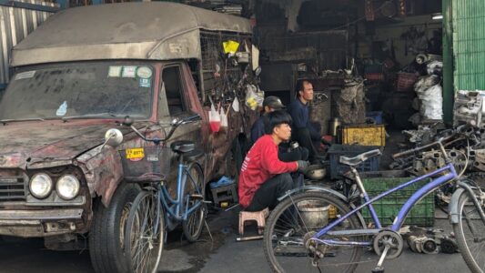 Portrait d'un enfant à côté d'un vélo et d'un camion dans une rue alternative de Bangkok