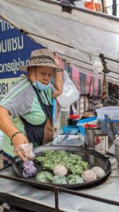 Portrait d'un vendeur de street food à Bangkok, souriant avec des boulettes colorées en arrière-plan